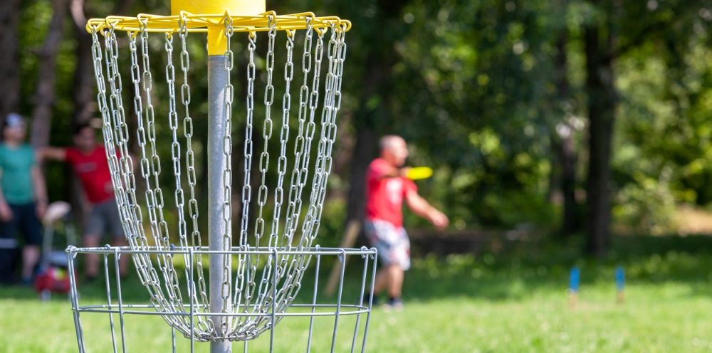 male playing disc golf in grass field