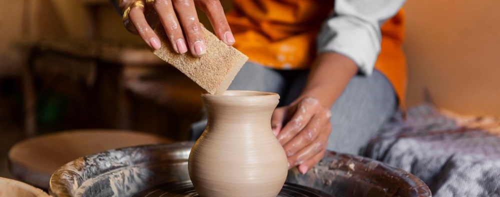 student with clay on a wheel making vase
