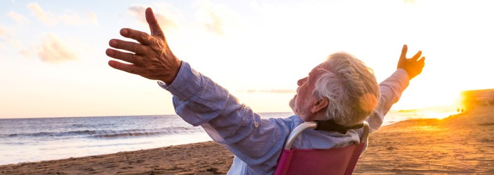 male senior citizens sitting on sand looking out to ocean
