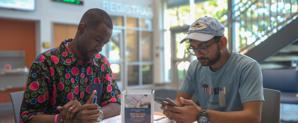 two male students in the student services building sitting at a table with open books studying