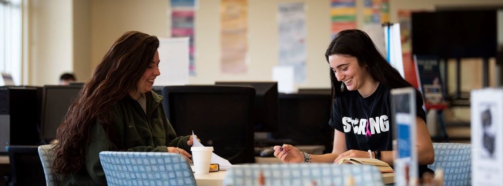 two female acc students sitting together at a table laughing