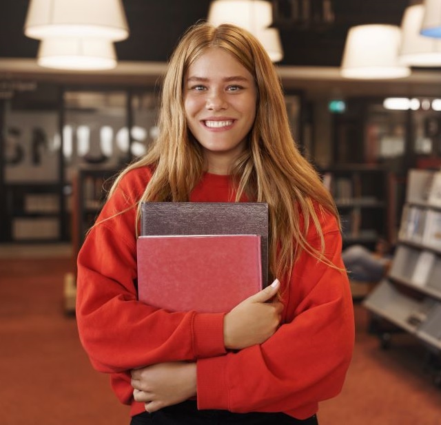 Smiling girl holding books at the bookstore