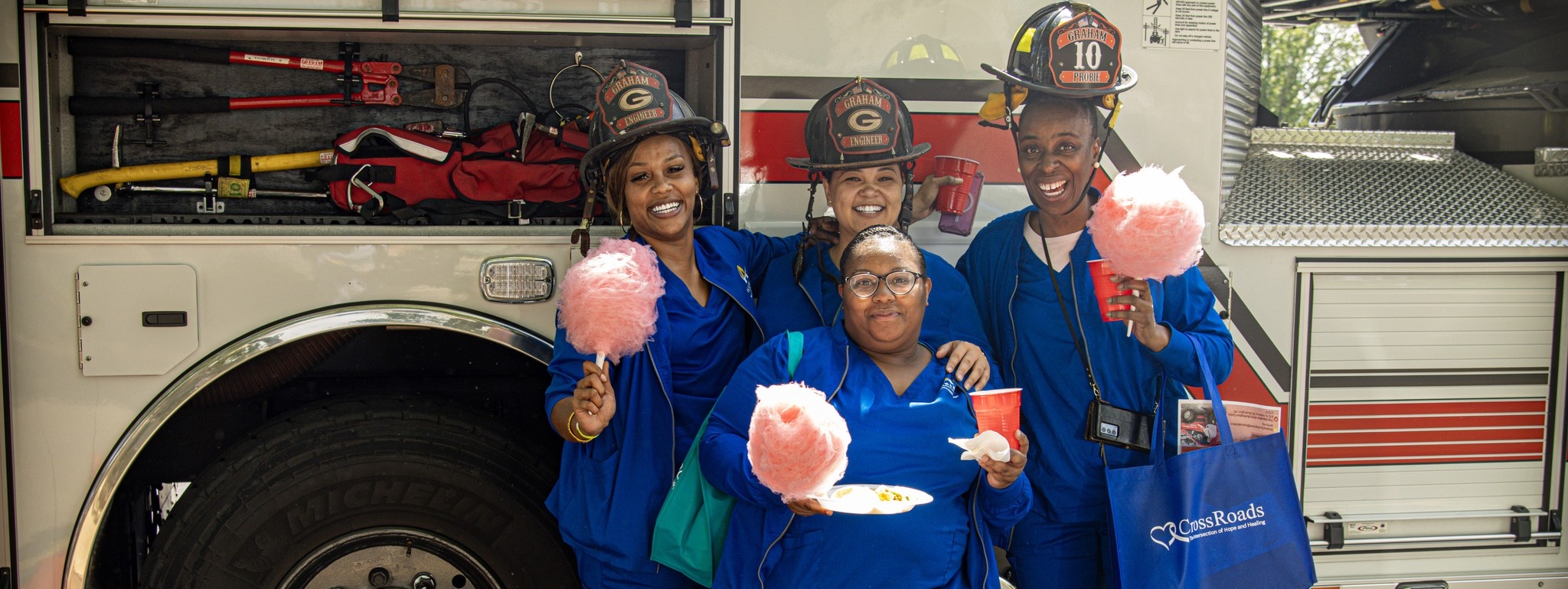 A group of three acc nursing student females at the spring fling. They are standing in front of a fire truck with cotton candy in their hands and smiling.