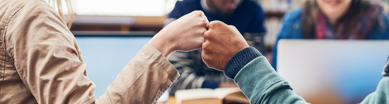 two young student giving each other a fist bump for a sign of support.