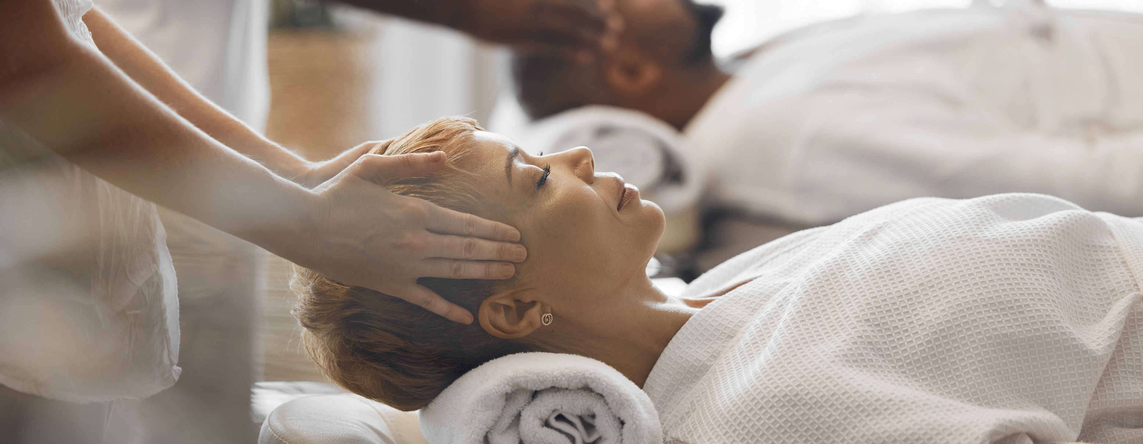 Massage therapist gently supports a client’s head during a massage therapy session.