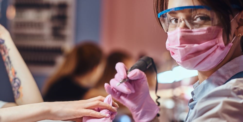 female nail tech student practicing on another female student